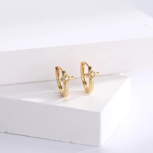 Detail view of gold S925 silver cross earrings with sparkling zircon on stone base