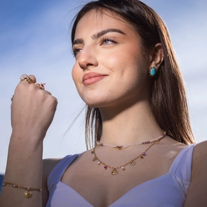 Layered gold necklaces with turquoise and pearl jewelry set against a blue sky