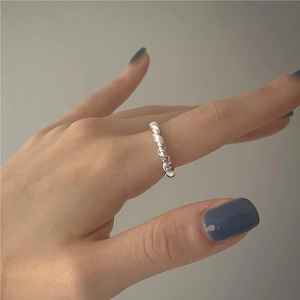 Detail of a minimalist 925 sterling silver knotted ring on a model hand with blue nails