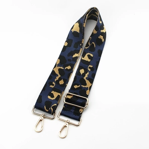 Macro view of leopard print wide bag strap featuring polished light gold metal lobster clasps
