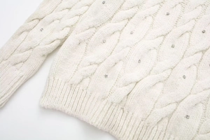 Detailaufnahme von Zopfstrickpullover mit funkelnden Strasssteinen und Rippsaum