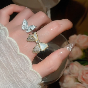 Macro detail of a 14k gold plated bow and flower ring with zircon inlays and shell texture