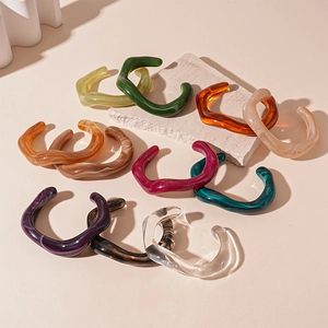 Irregular wavy acrylic bangles in assorted marble colors on a textured stone display