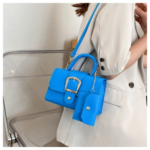 Detail of bright blue textured leather crossbody bag with gold buckle and mini pouch