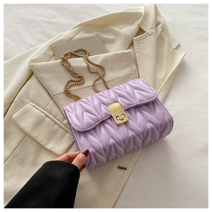 Detail of purple matelassé crossbody bag with gold chain strap on cream blazer