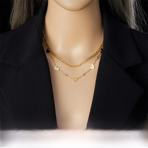 Detail of layered gold-plated stainless steel necklace with heart pendant on a model