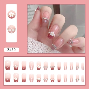 Detail of pink gradient press-on nails with 3D floral accents and shimmering glitter