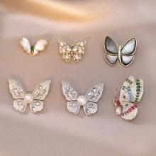Detail view of butterfly brooches with zircons and tassels on silk fabric background