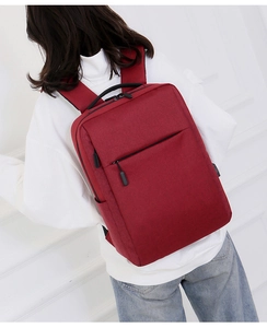 Rear view of a red nylon laptop backpack shown on a model with USB charging port