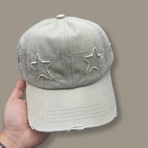 Detail of star embroidery and distressed ripped brim on beige vintage baseball cap