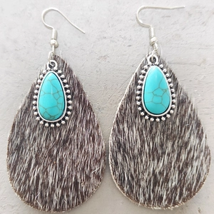 Macro shot of teardrop earrings with cowhide fur textures and turquoise stone details