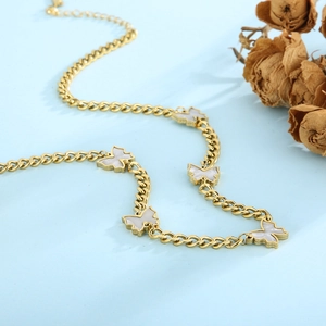 Close-up of gold curb chain necklace with white butterfly charms on light blue background