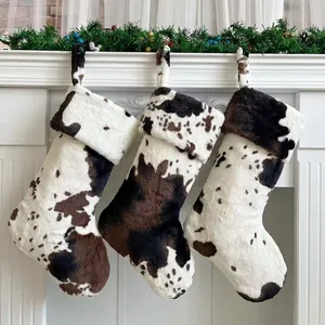 Three plush cow print Christmas stockings on a festive white fireplace mantel decor