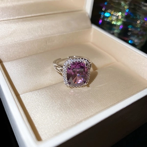 Macro shot of cushion-cut purple gemstone ring with diamond halo and filigree band detail