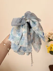 Detail of floral bow hair claw with blue ribbons, large pearls and dangling bead tassels
