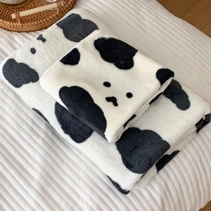 Detailed texture of thick cow pattern coral fleece bath towel set on white bedding