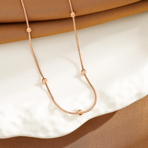 Elegant 18K rose gold snake bone chain necklace with small beads on white ceramic