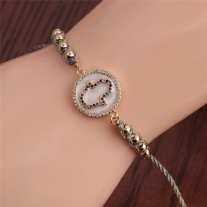 Close-up of Hamsa hand charm on a hand-woven bracelet with colorful cubic zirconia