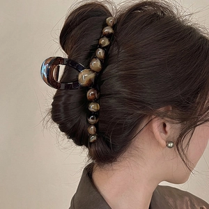Détail d'une pince à cheveux en écaille foncée fixant les cheveux sur un modèle