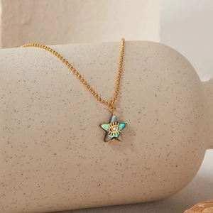 Detail of gold bead chain necklace with abalone shell star pendant and evil eye motif