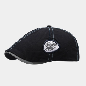 Detail of British style newsboy cap showing blue contrast stitching and vintage embroidery