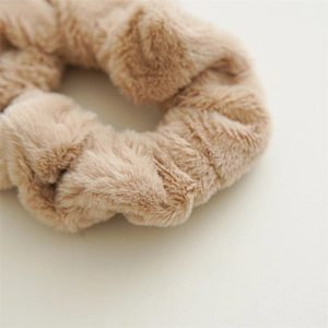 Macro detail of a light brown faux fur scrunchie showing soft plush texture and creases