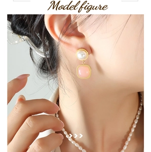 Close-up of elegant pearl necklace and pink gemstone earrings worn by a model