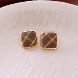 Détail macro de boucles d'oreilles carrées en tissu avec cadre doré et motif à carreaux