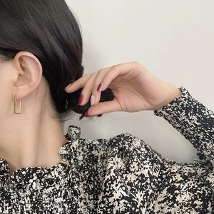 Macro shot of gold rectangle drop earrings on a model showing minimalist geometric design