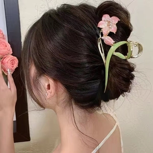 Elegant tulip claw clip in pink and green metal finish securing a bun hairstyle
