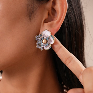 Gros plan de boucles d'oreilles fleurs avec émail, strass colorés et perle centrale