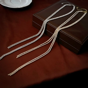 Luxurious double-layered rhinestone tassel necklace in gold and silver on silk backdrop