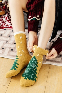 Detail of plush ginger yellow Christmas socks with green tree pattern and cozy lining