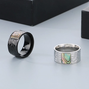 Detailed macro view of men's stainless steel rings with hammered texture and abalone shell inlay