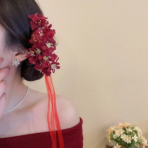 Detailed back view of large red fabric flower hairpins with long flowing ribbons