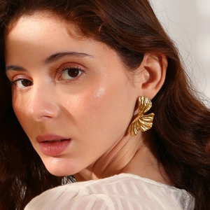 Golden ginkgo leaf stud earrings in 18K gold plated stainless steel on a female model