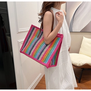 Lifestyle shot of model carrying a large colorful striped woven beach tote bag