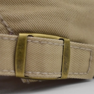Detailed macro view of khaki cotton beret with vintage bronze metal adjustable buckle