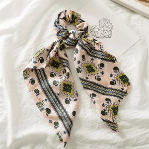 Detailed close-up of pink satin hair scrunchie with geometric patterns and blue stripes