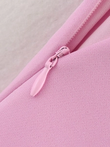 Gros plan d'une fermeture éclair invisible rose sur un haut cintré en tissu texturé