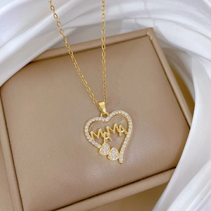 Macro view of golden heart MAMA pendant with zircons on soft white silk background