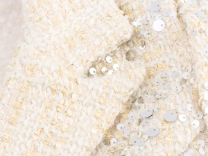 Détail du tissu en tweed blanc cassé avec paillettes argentées et fils dorés