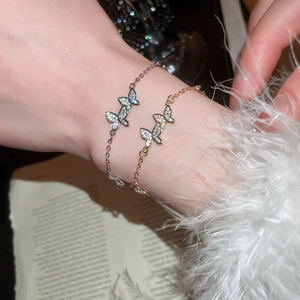 Detailed close-up of double butterfly bracelet with white zircon in gold and silver finish