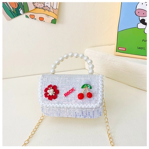 Détail du sac enfant avec poignée perle, bordure dentelle et breloques cerise
