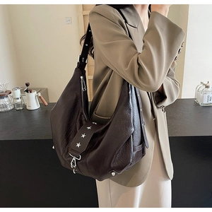 Detail of dark brown leather tote bag with silver star rivets on a beige blazer model