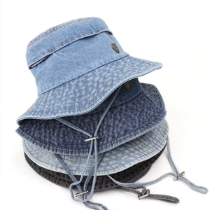 Close-up of denim bucket hats with metal shield logo and adjustable windproof cords