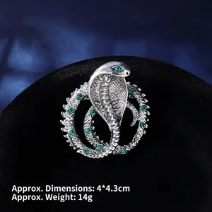 Detail of silver cobra brooch with green emerald gems and snake skin texture