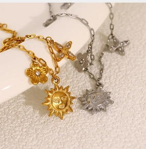 Détails de colliers soleil et fleur diamantée or et argent sur céramique blanche