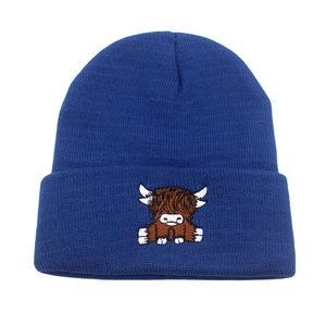 Detailed close-up of dark blue knit beanie with highland cow embroidery pattern