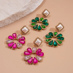 Dettaglio di orecchini a fiore con gemme a goccia e perle finte quadrate con strass